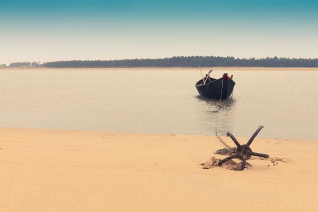 anchor on the sand connected to small boat in the water