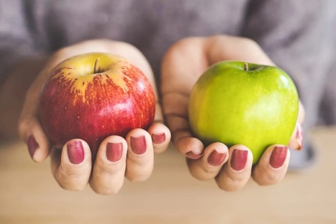 hands holding a red and green apple