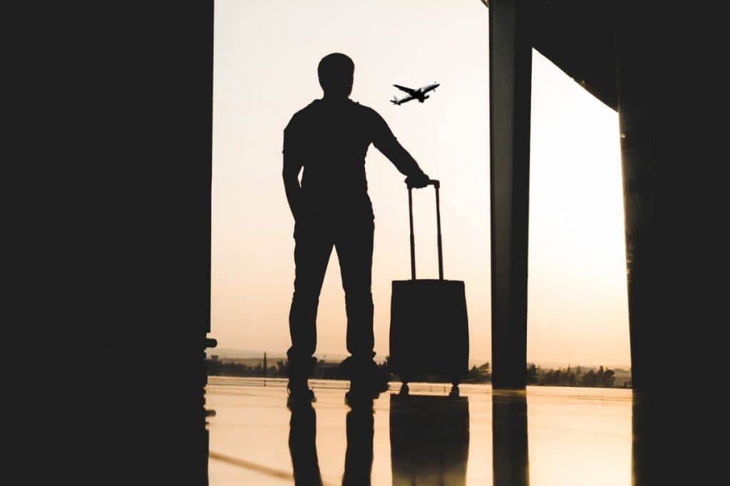 silhouette of man with a suitcase watching an airplane