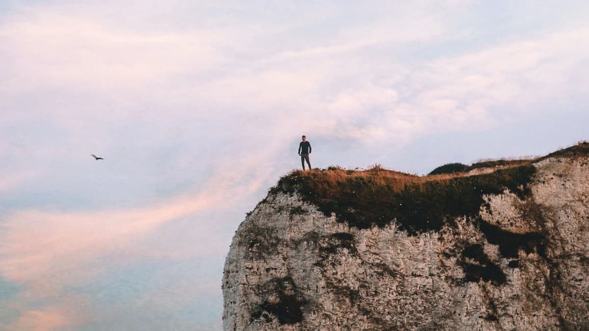 silhouette of man standing on edge of rock